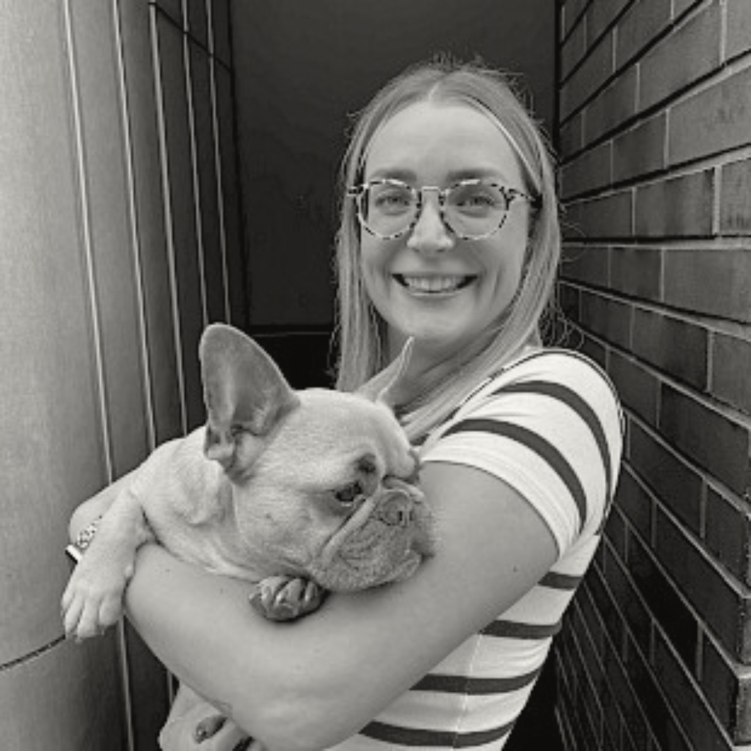 Smiling picture of Harriet Edge-Partington holding a dog.