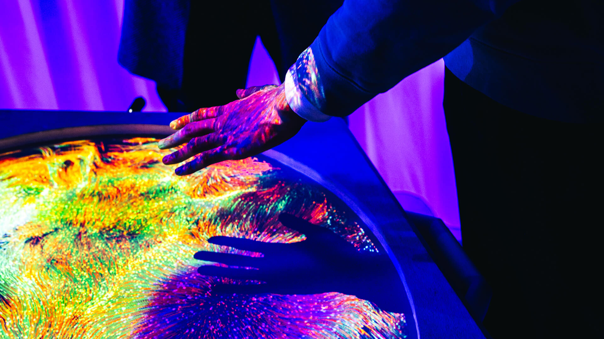 Person reaching out their hand towards digital artwork at an observatory installation