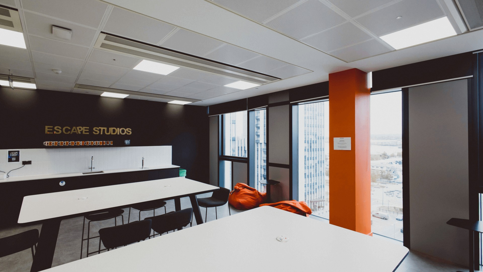 Escape Studios breakout space with tables and chairs and kitchen in the background