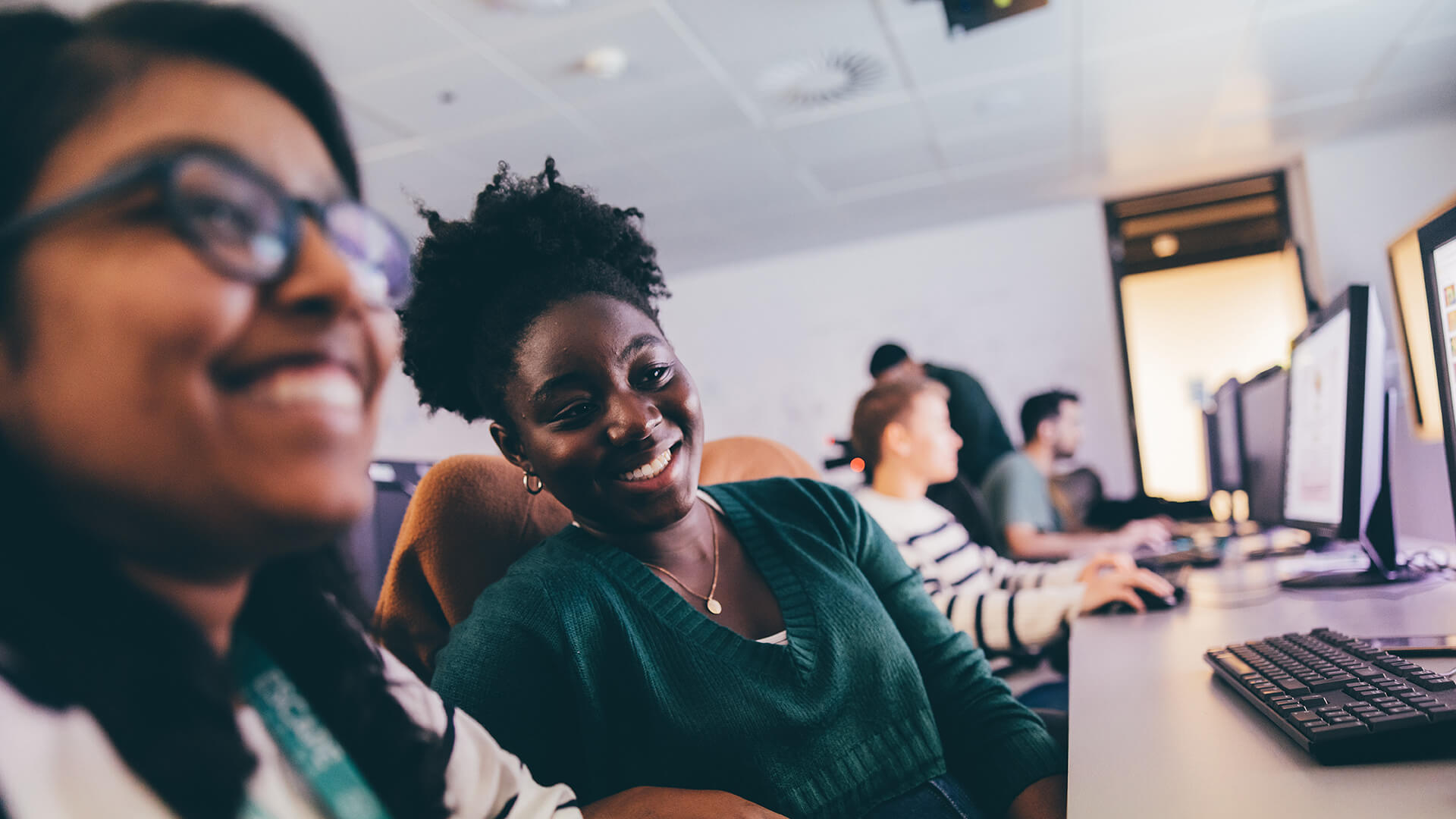 Female student laughing at computer monitor