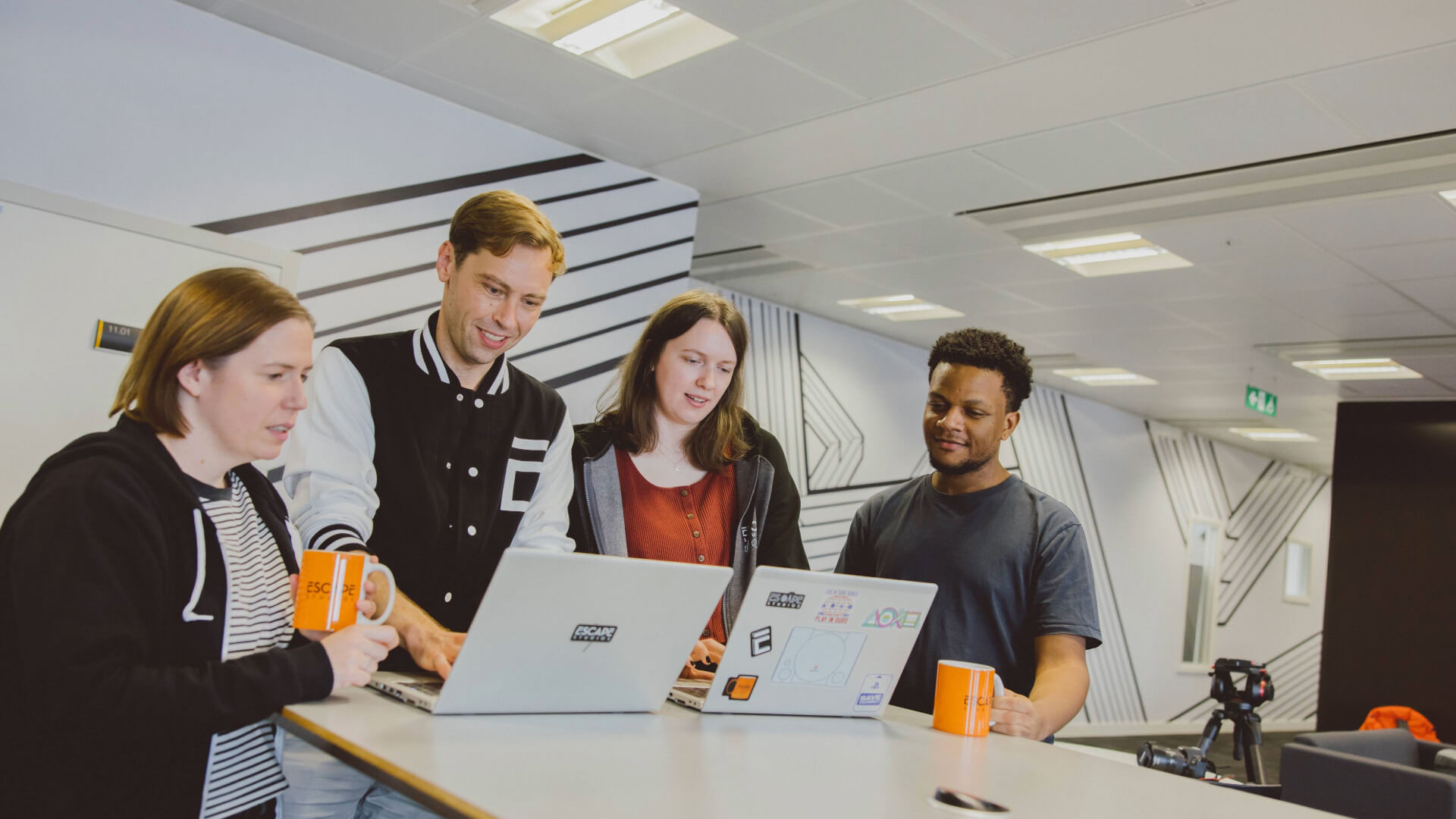 Postgraduate students looking at laptops on breakout space table