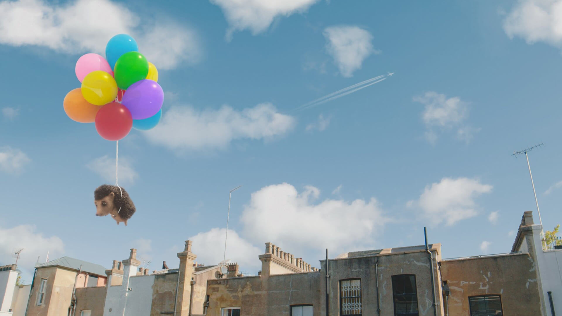 Animated hedgehog floating above street scene using balloons