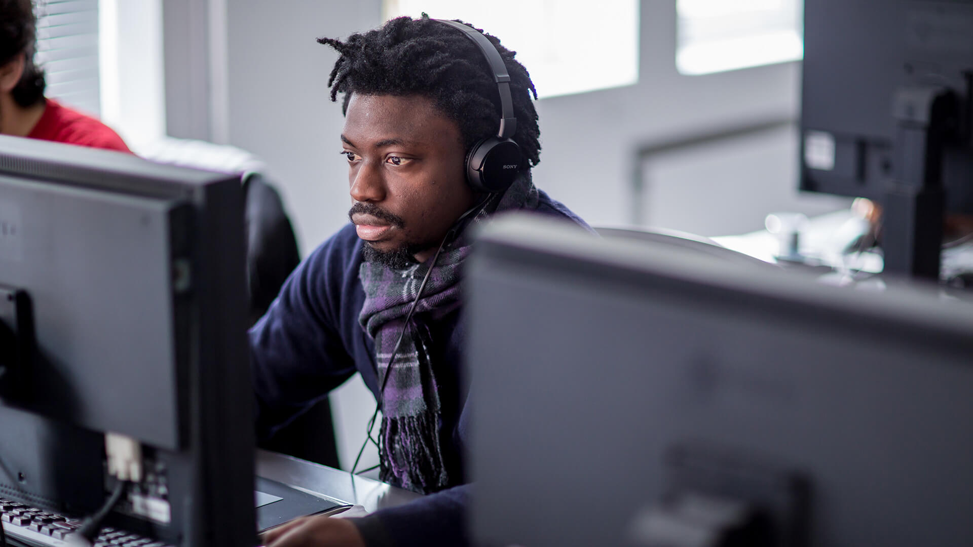Male student sat behind computer monitor