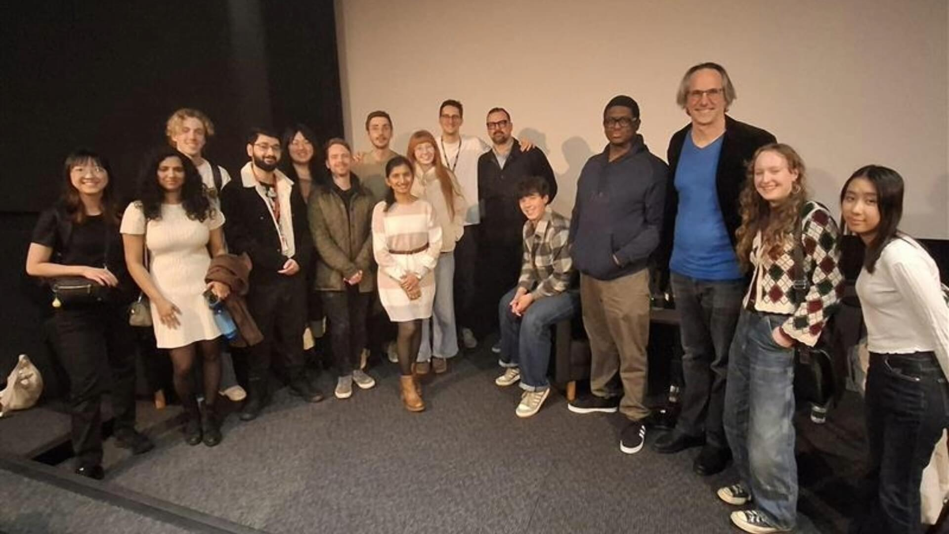 A group picture showing a student group visiting DNEG's London studio. They are pictured with Senior Director of Training and Development at DNEG Andrew Schlussel, who is stood towards the right of the group in a blue shirt.