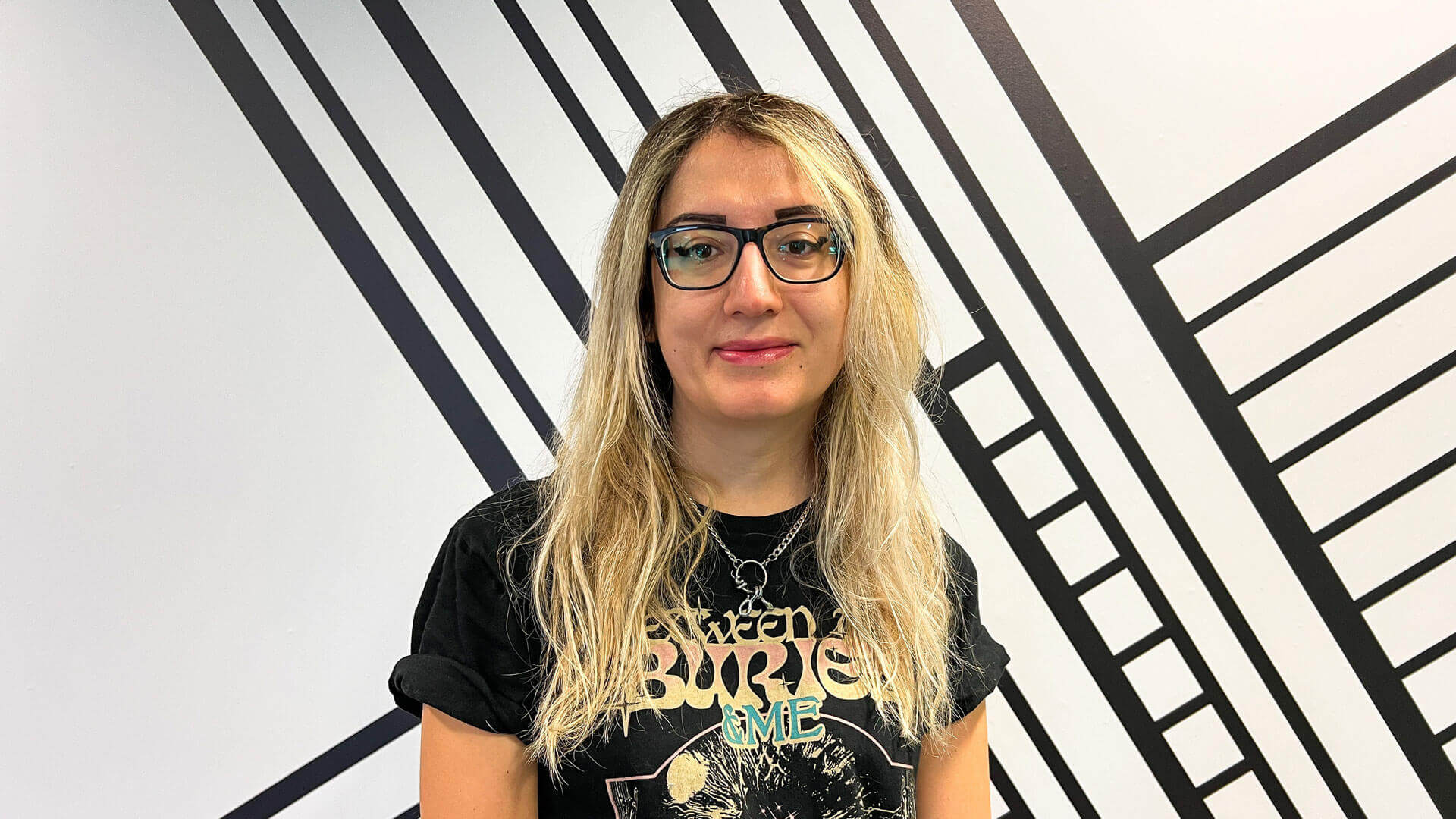 A head and shoulders picture of Motion Graphics Tutor Bella Cologlu smiling in front of the black and white escape studios wall art