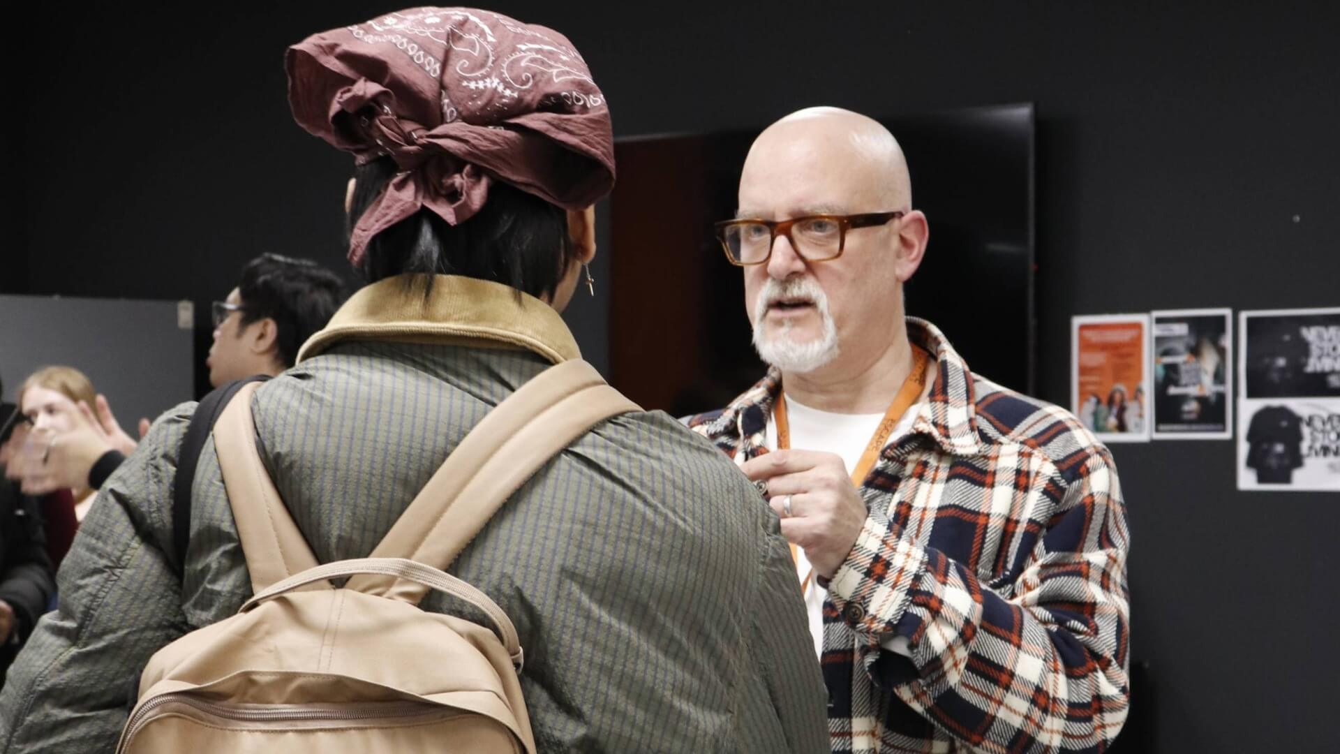 Tutor explaining to prospective post graduate student at an open evening