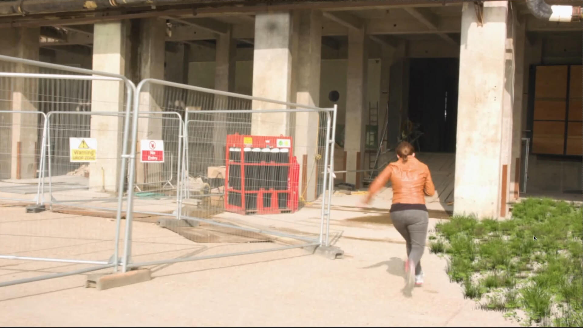 a screenshot showing a scene where a woman runs towards a concrete building, and grass is added to the ground in nuke