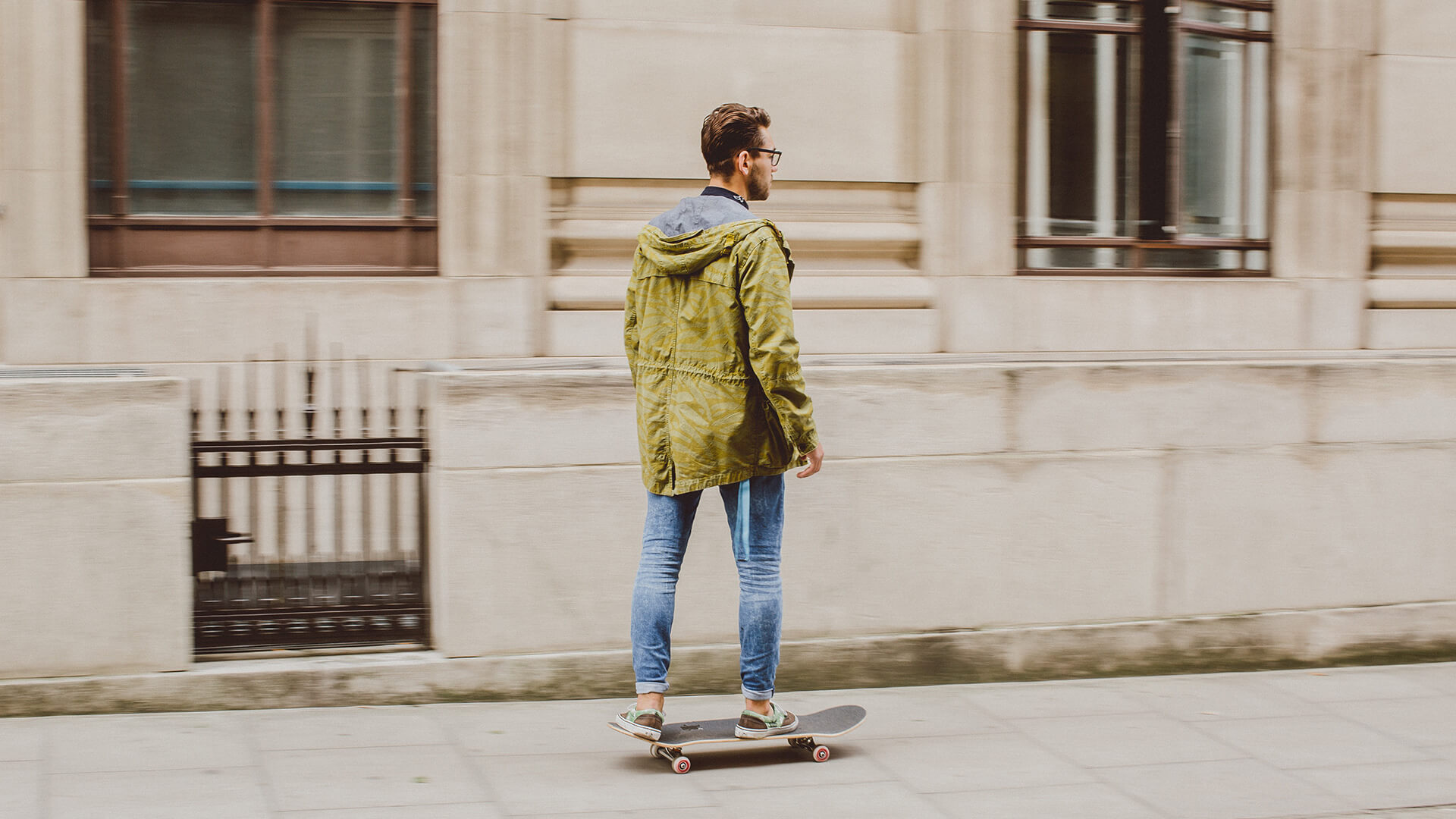 Male student skateboarding along the pavement
