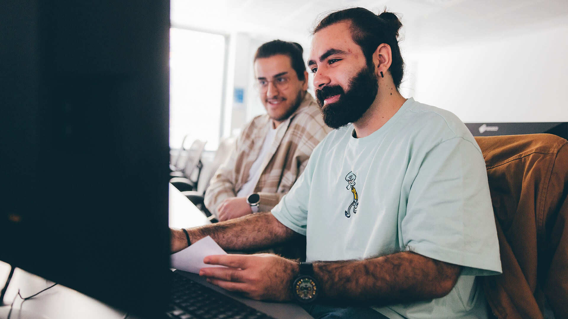 Two male students looking at a computer monitor