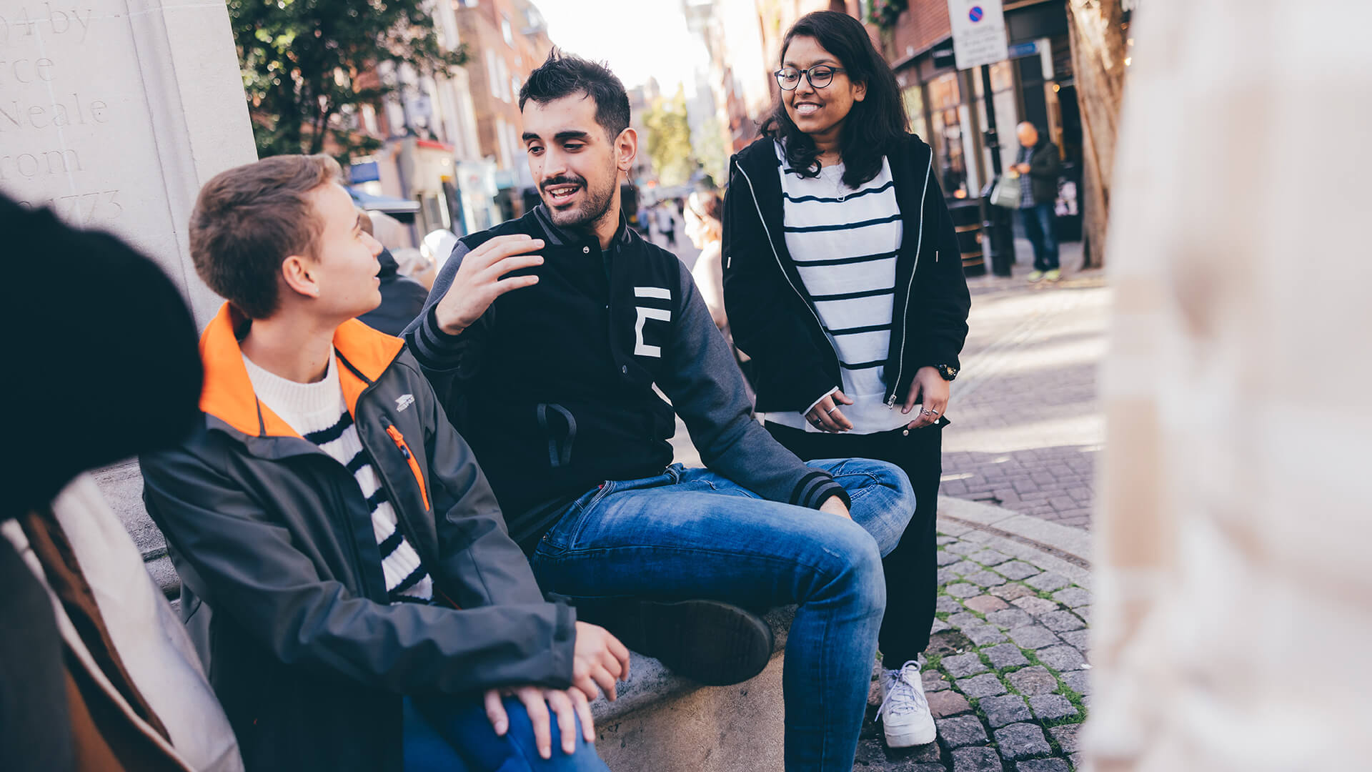 Three students chatting at stone seating area