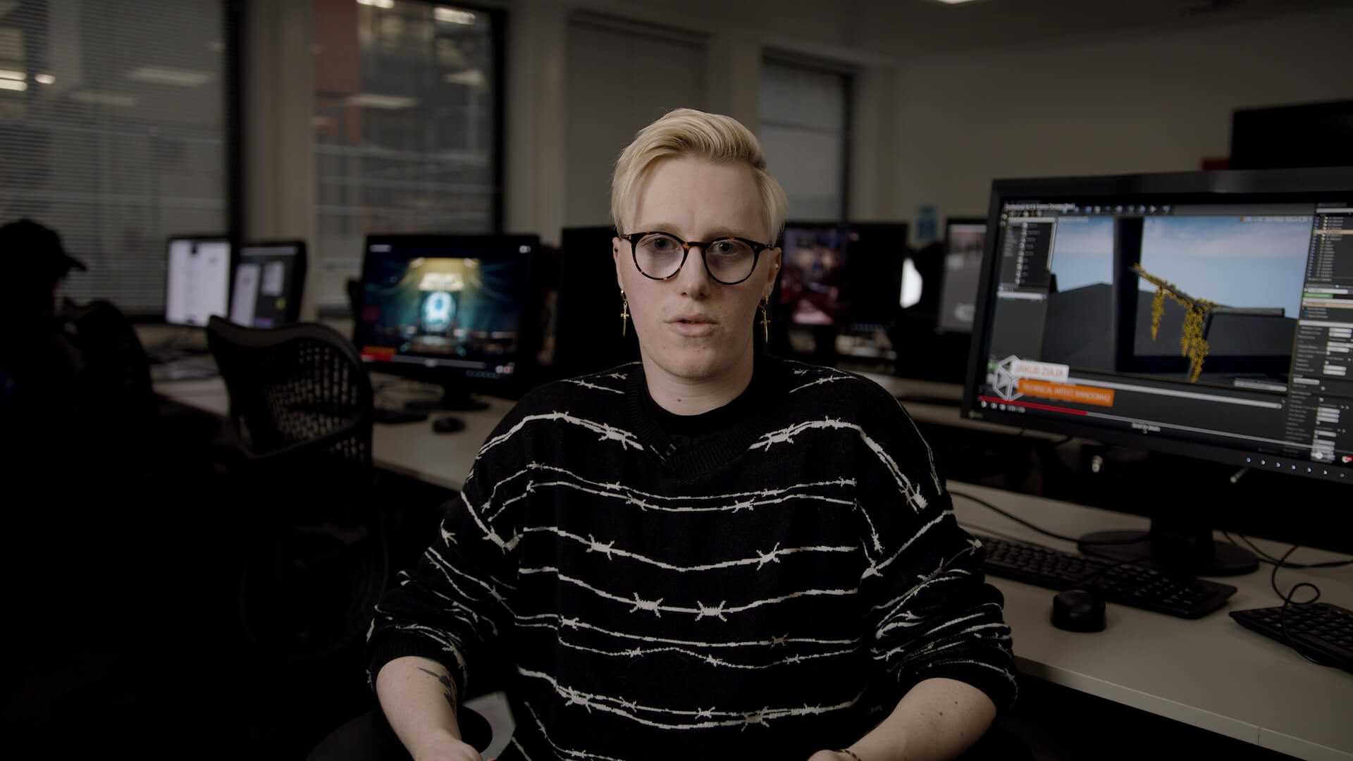 Alumnus and Framestore Technical Artist, Juriaan Van Vali sat in a studio with computers showing student work behind him