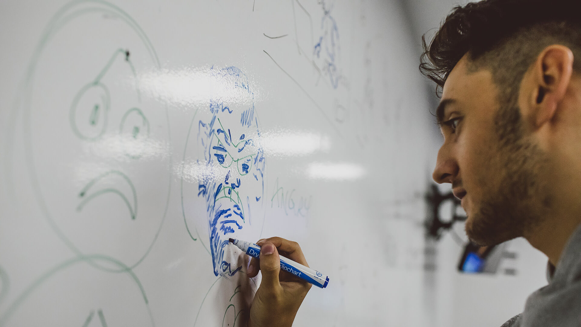 Male student drawing on character on a whiteboard