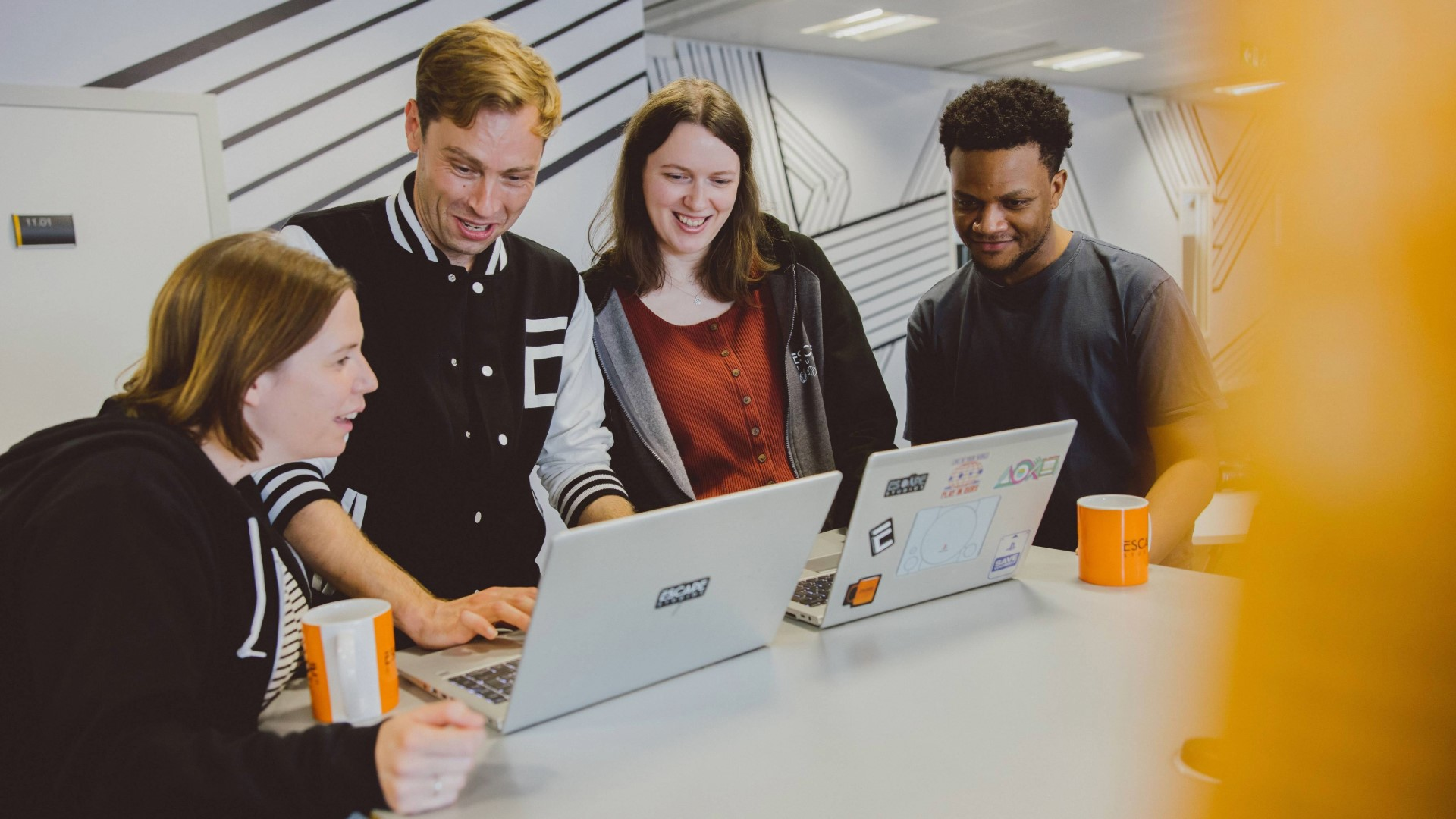 four students working on laptop