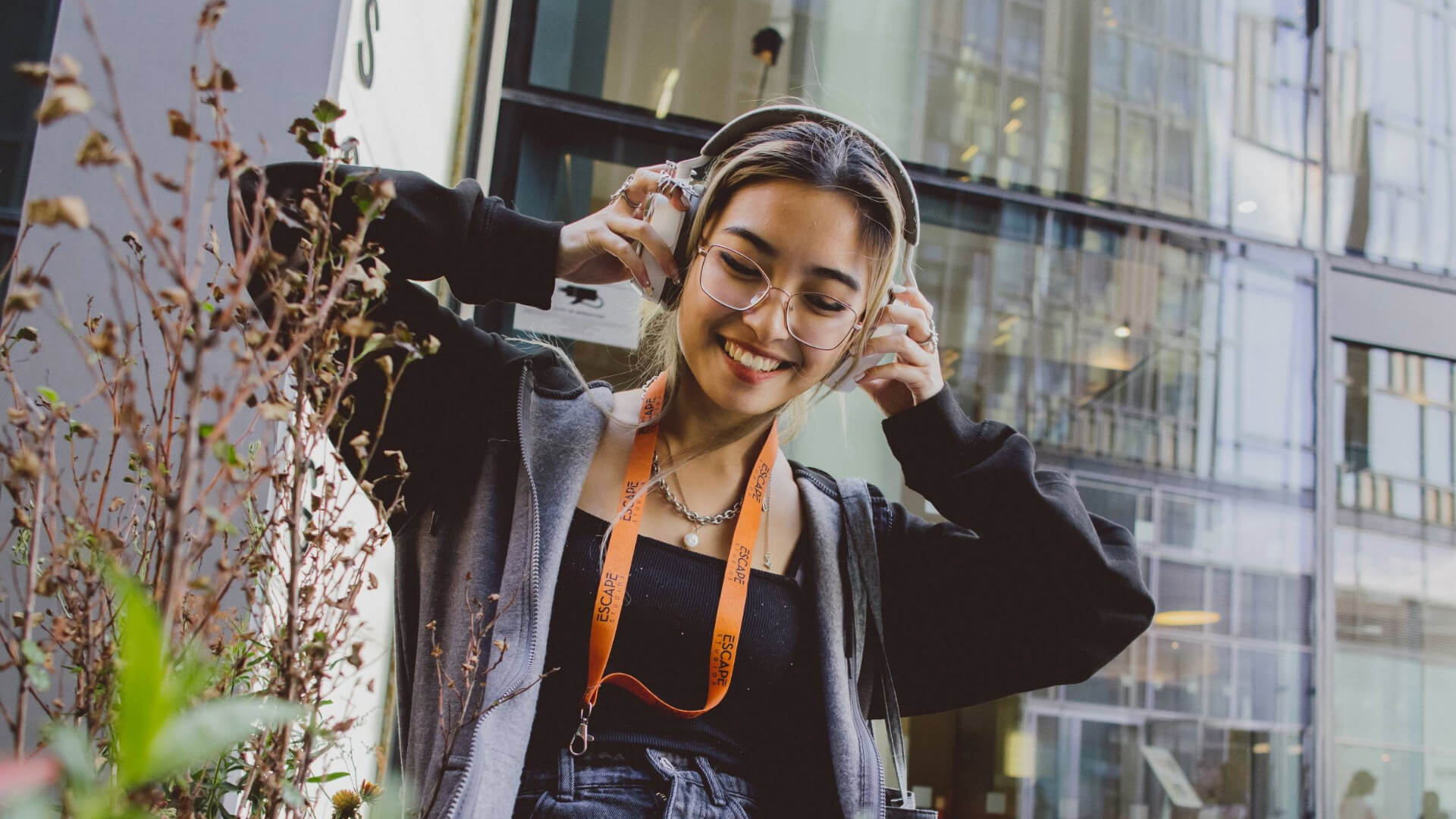 student with headphones listens to music outside Escape studios campus