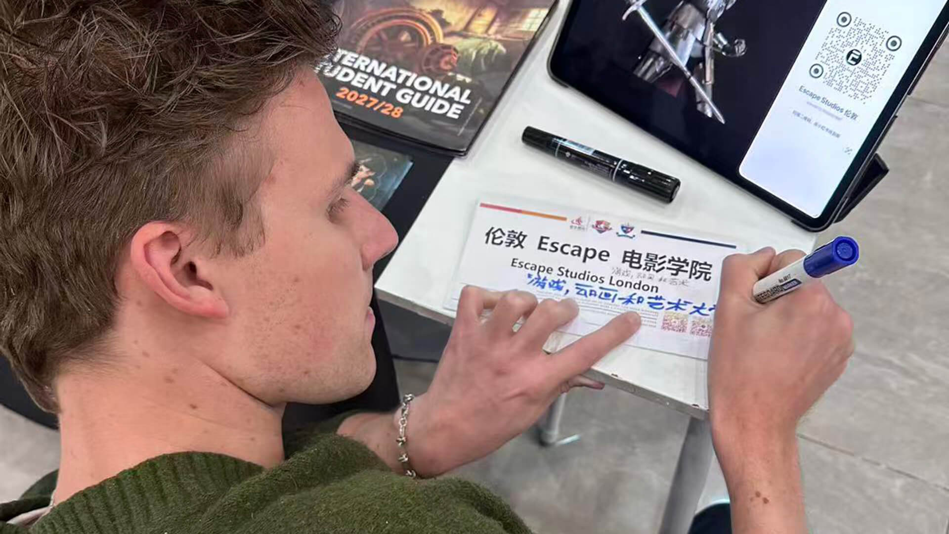 Staff member working at an international outreach fair in China, sat writing at a table
