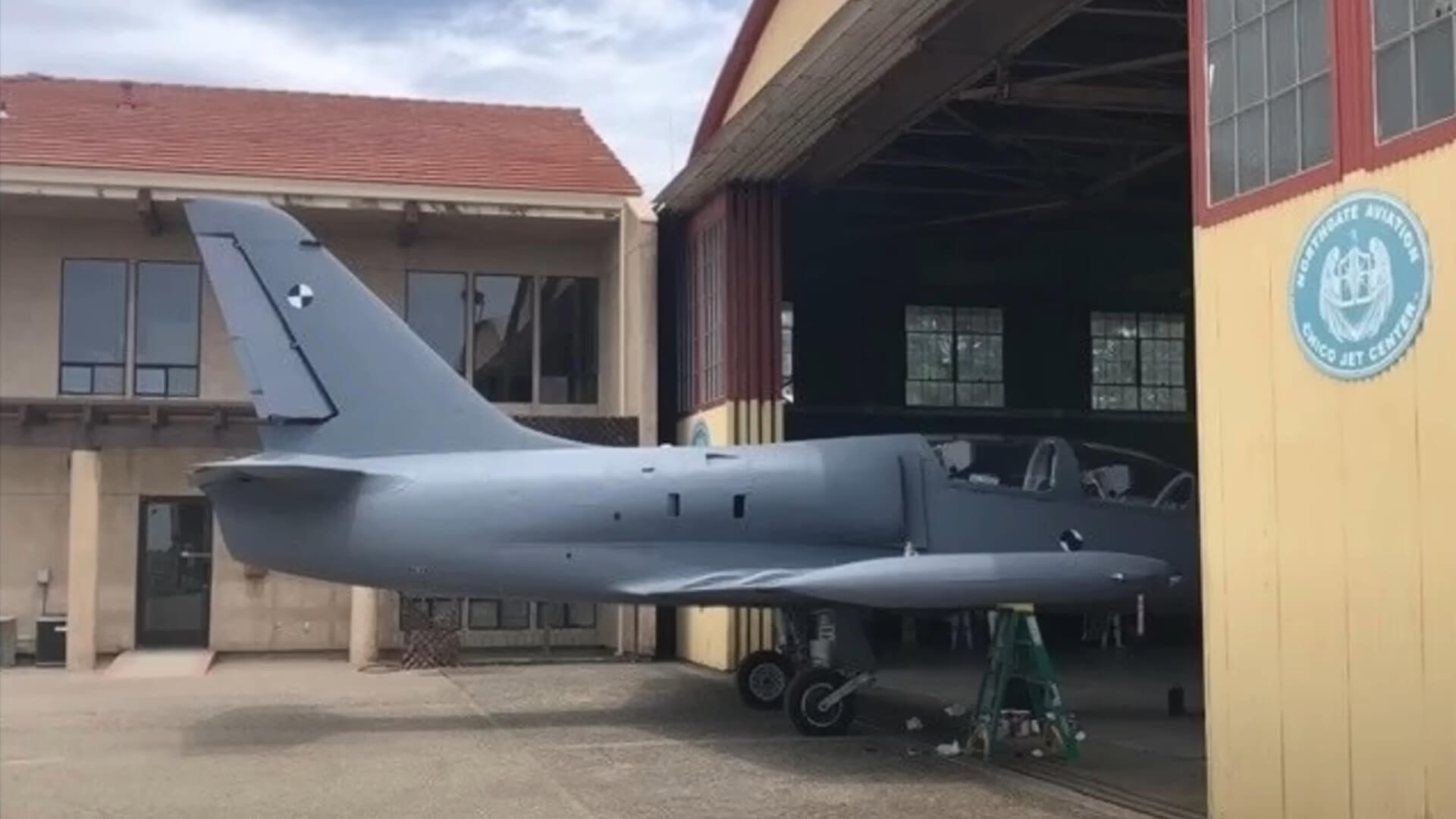 A grey fighter jet in a hangar, with markers on the side and tail